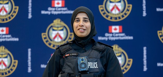 A female police officer in a Hijab speaks at a podium