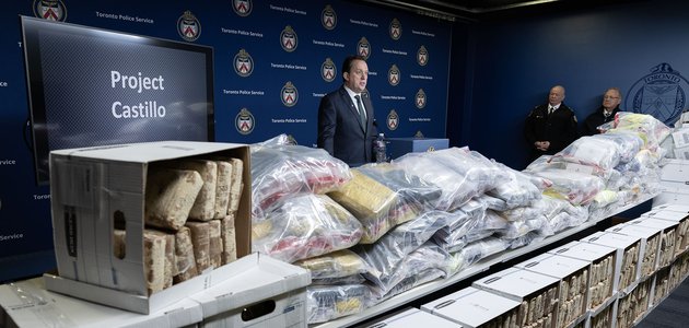 Person at podium behind packaged drugs