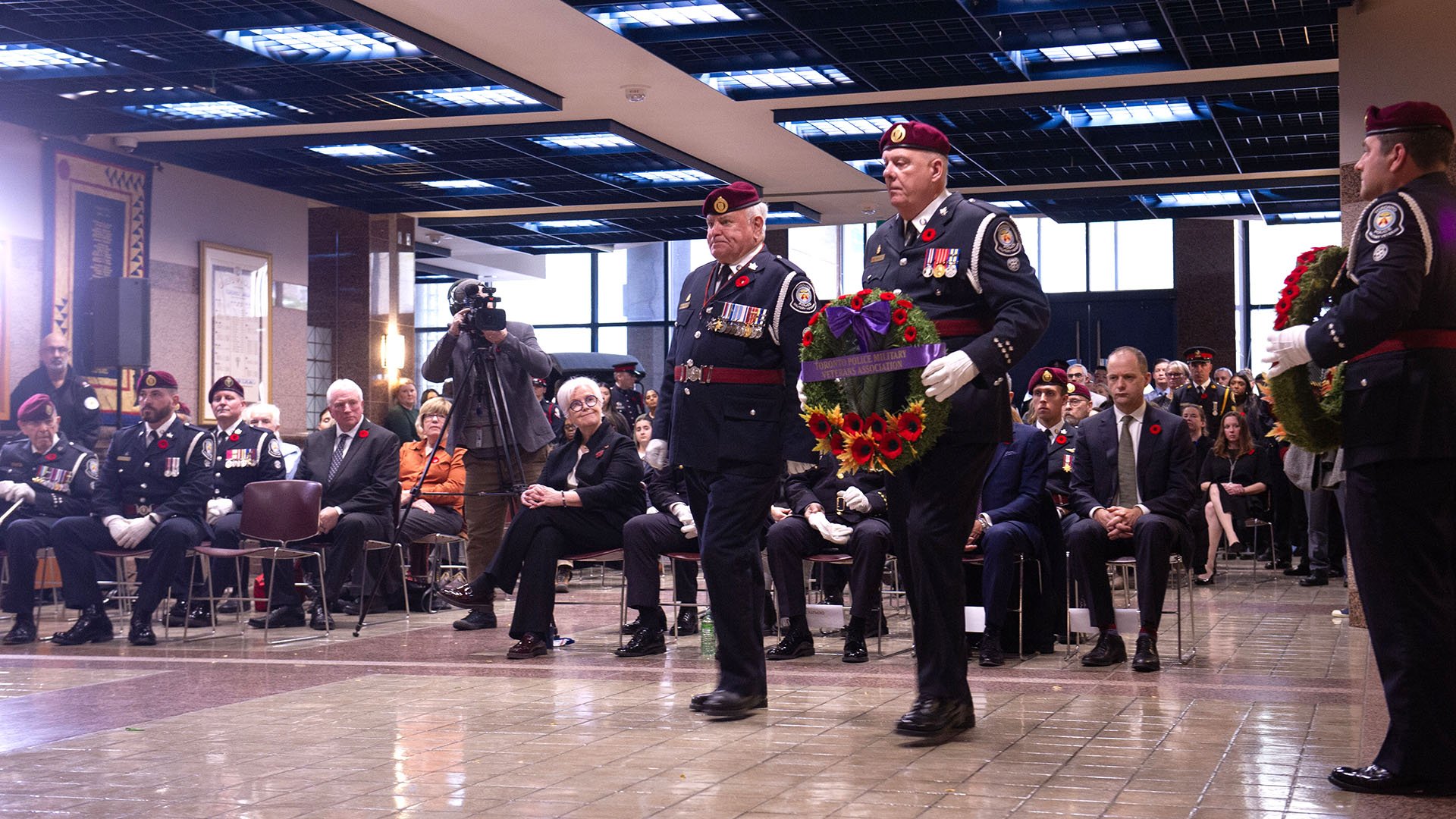 Two uniformed people walk with a wreath