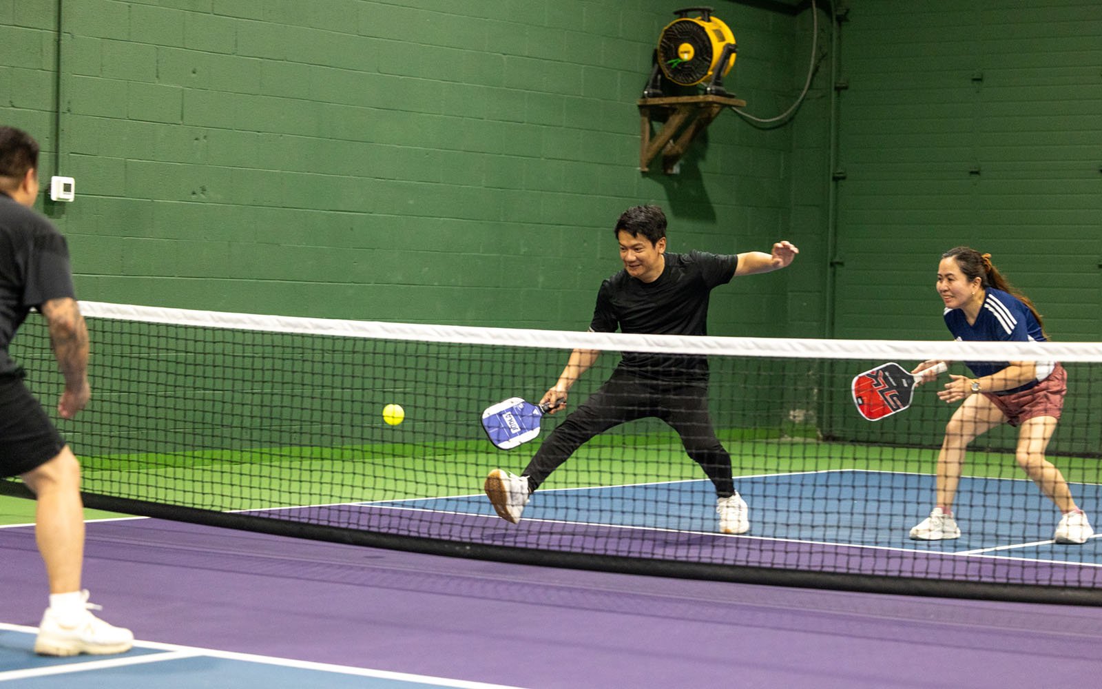 two men and a woman playing pickleball