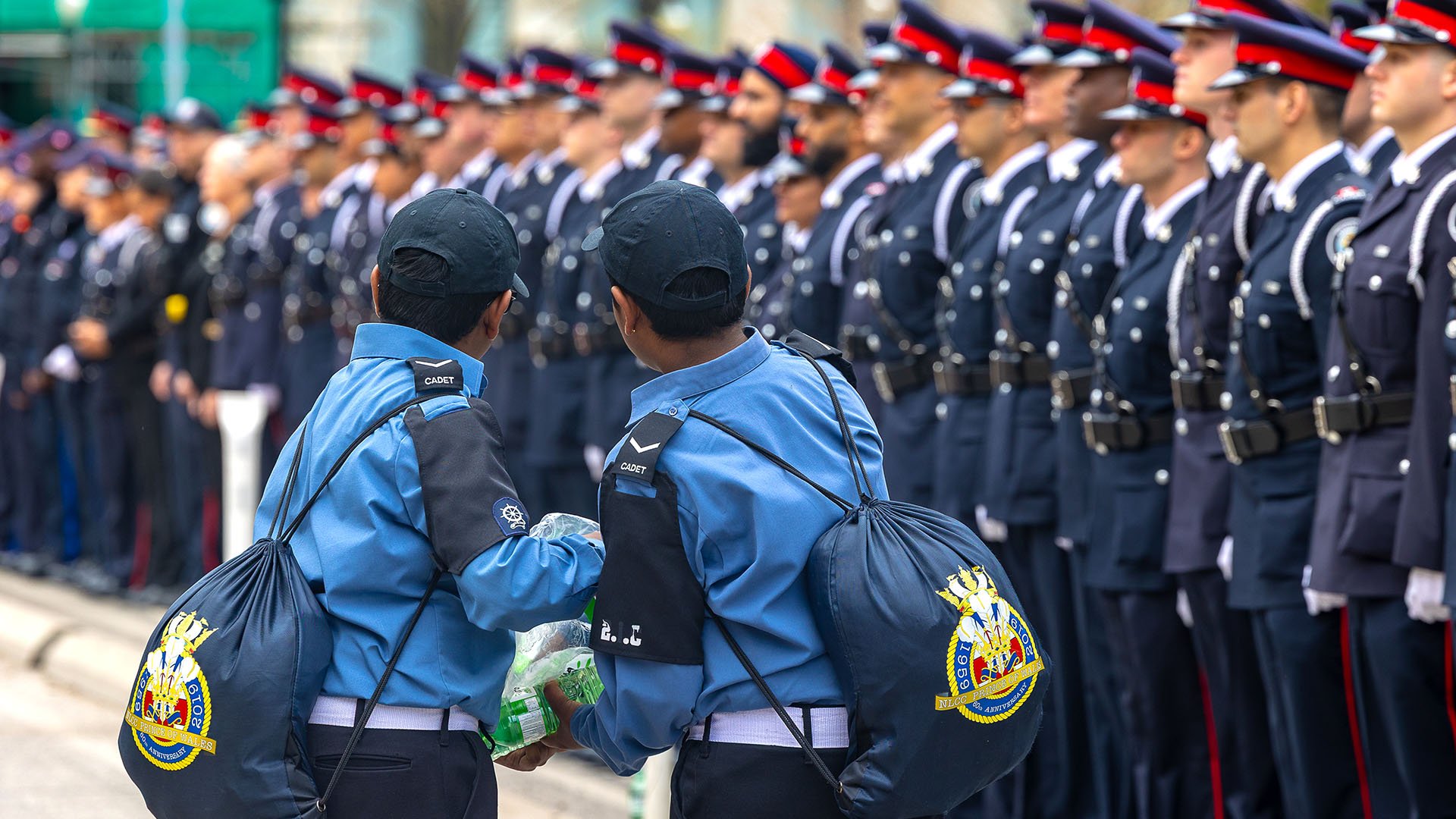 Two children in uniform in front of a line of police officers