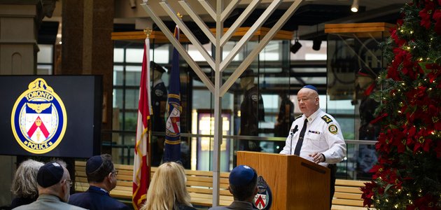 Police officer stands beside large menorah.