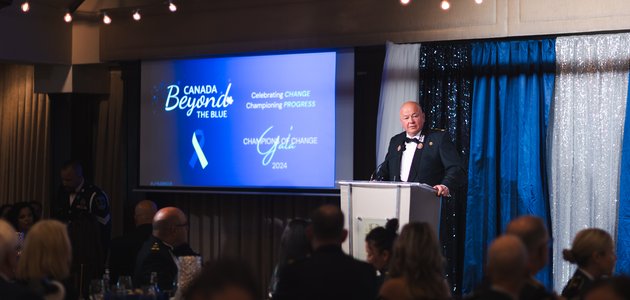 Man in a suit speaks to a room full of people