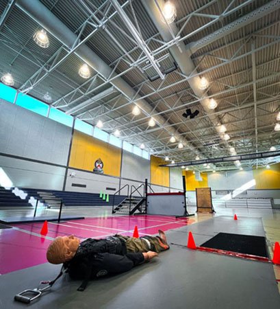 photo of a large gymnasium with a manneuqin lying on the floor