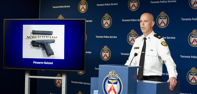 Police officer at a podium near photo of handgun