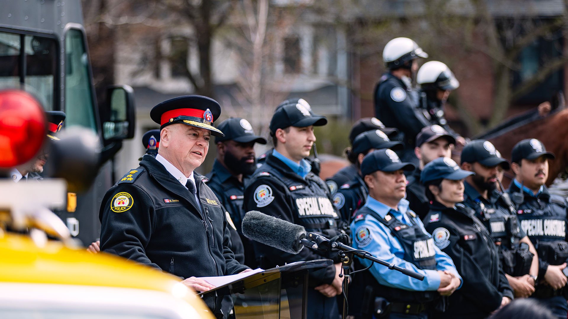 Police officer at a podium with other TPS members
