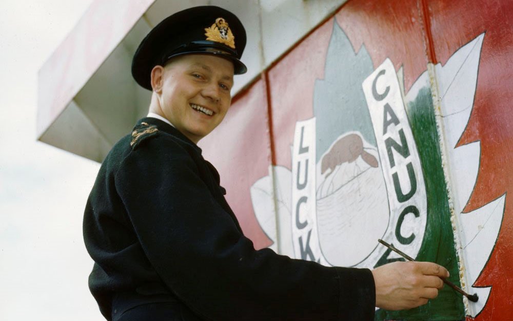 Naval officer painting a logo on a metal wall