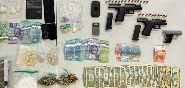 Handguns, cash, drugs in plastic bags on a table