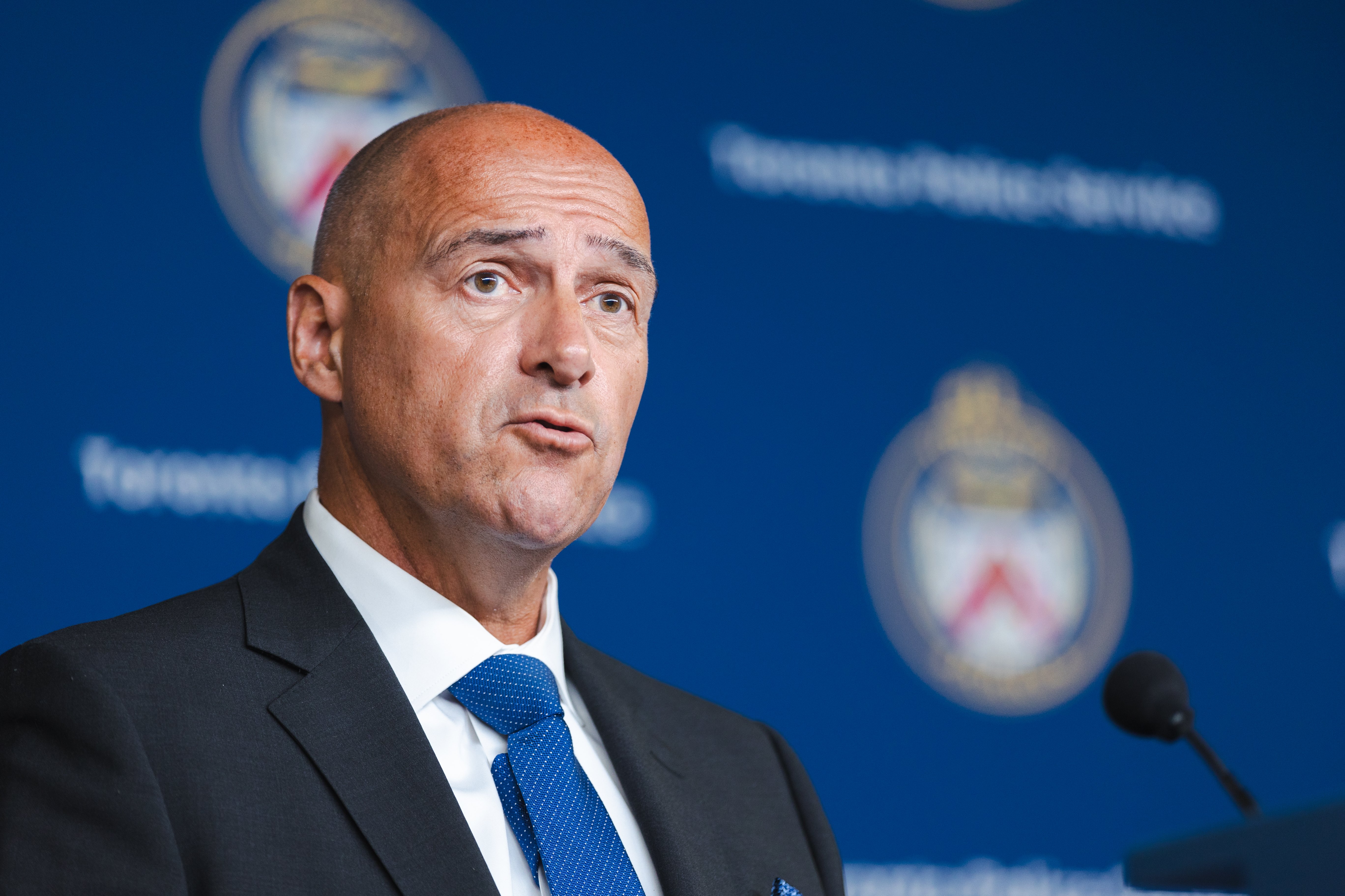 A man in a suit speaks into a microphone