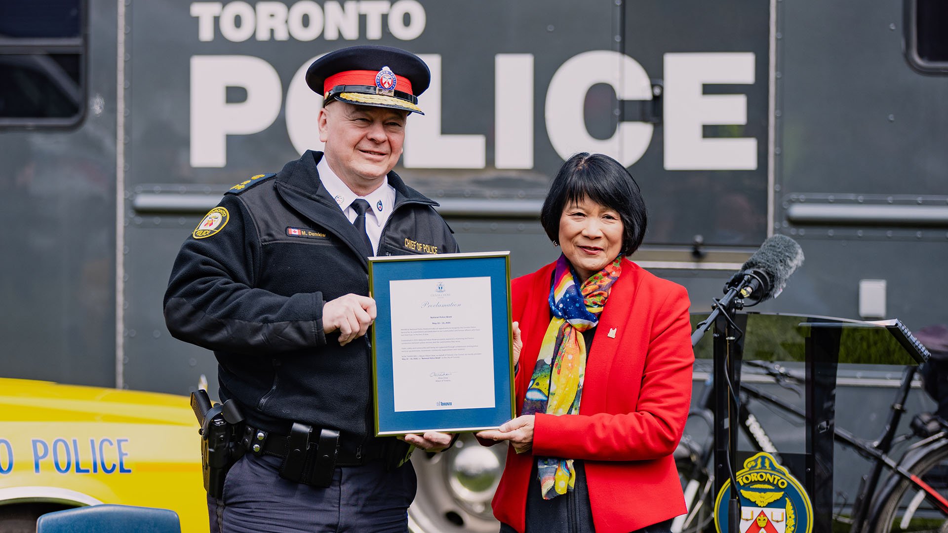 Two people hold a framed certificate