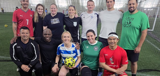 group of men and women in soccer outfits in an indoor field