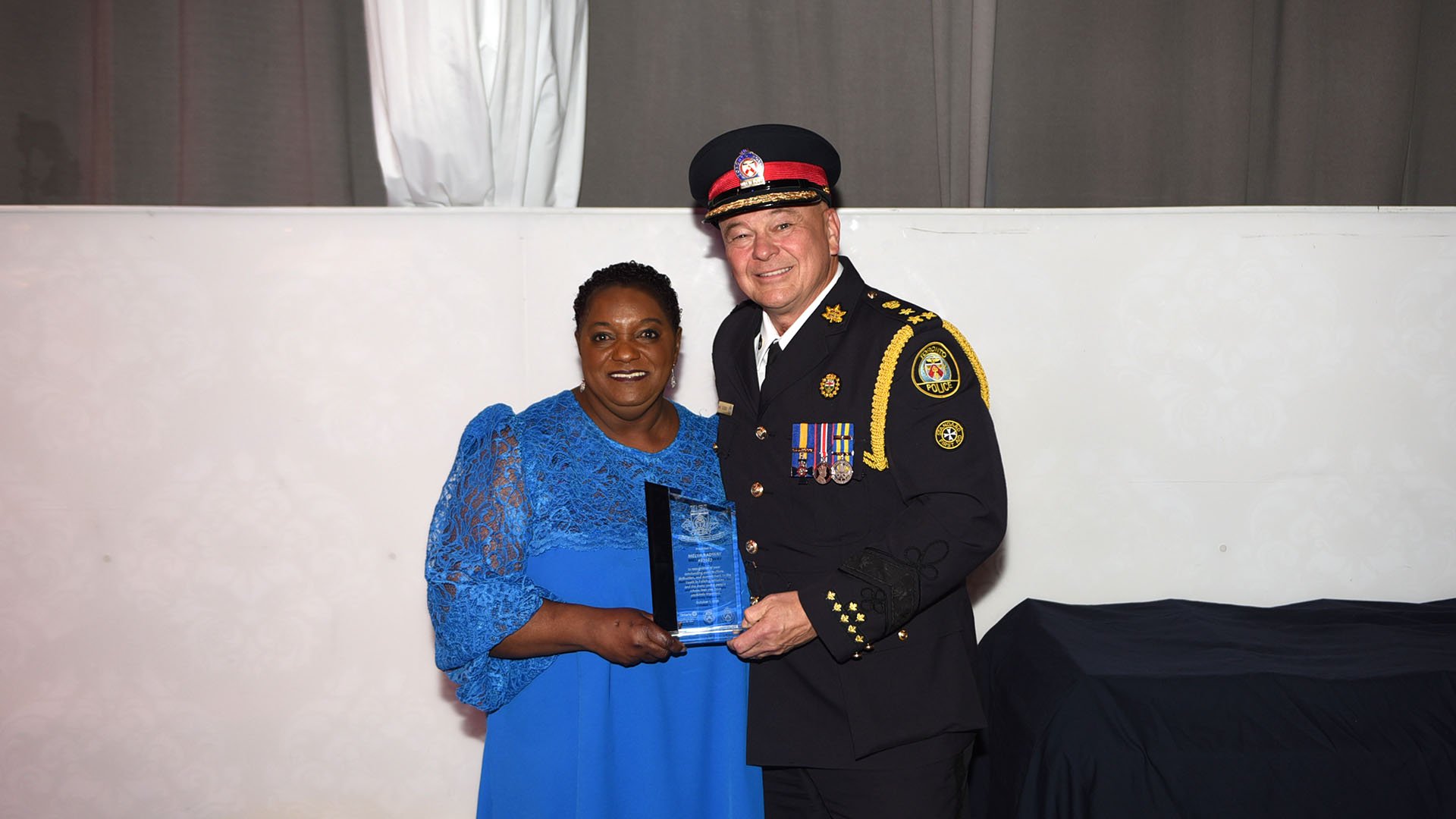 Two people stand with an award