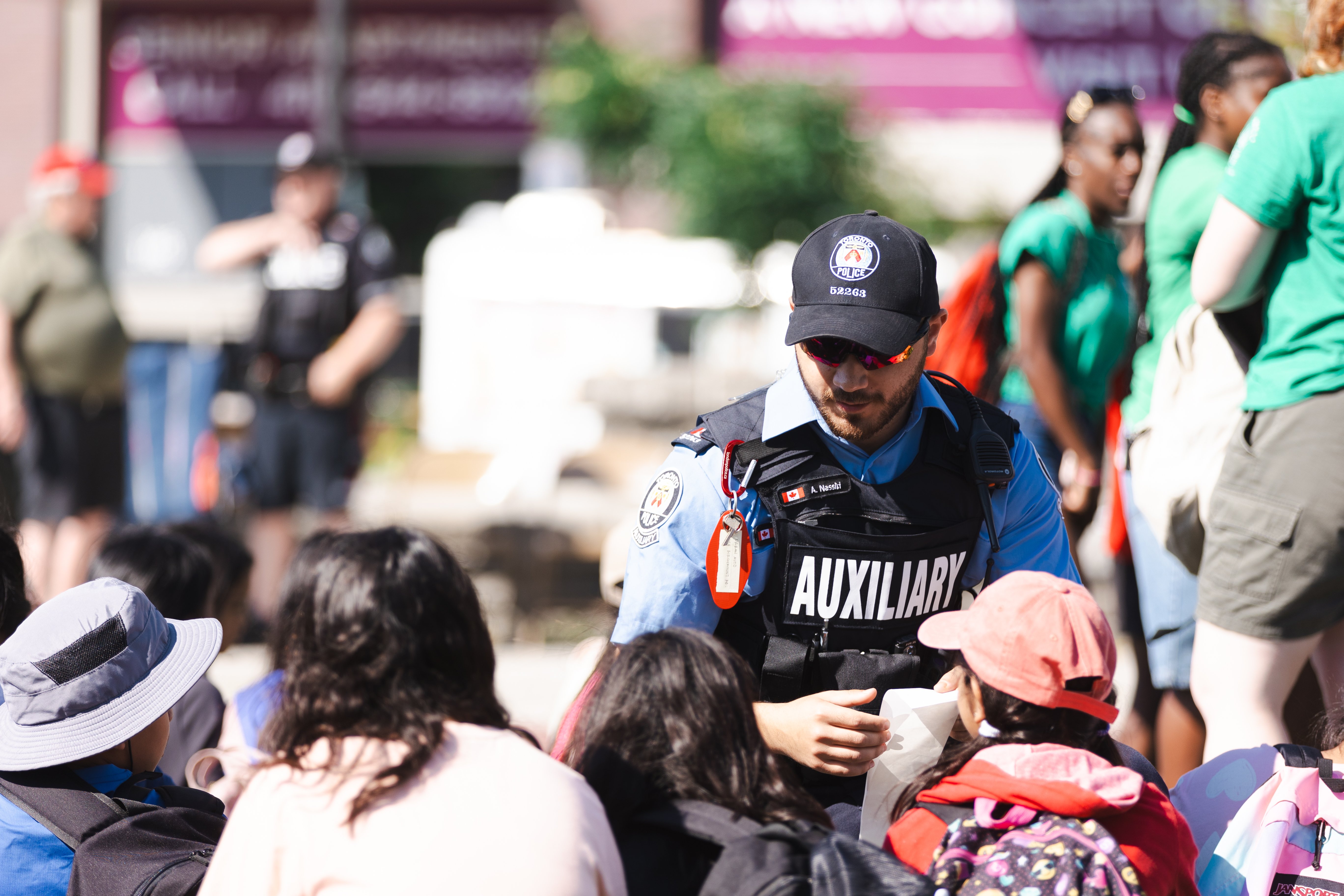 An auxiliary officer kneels next to kids and smiles