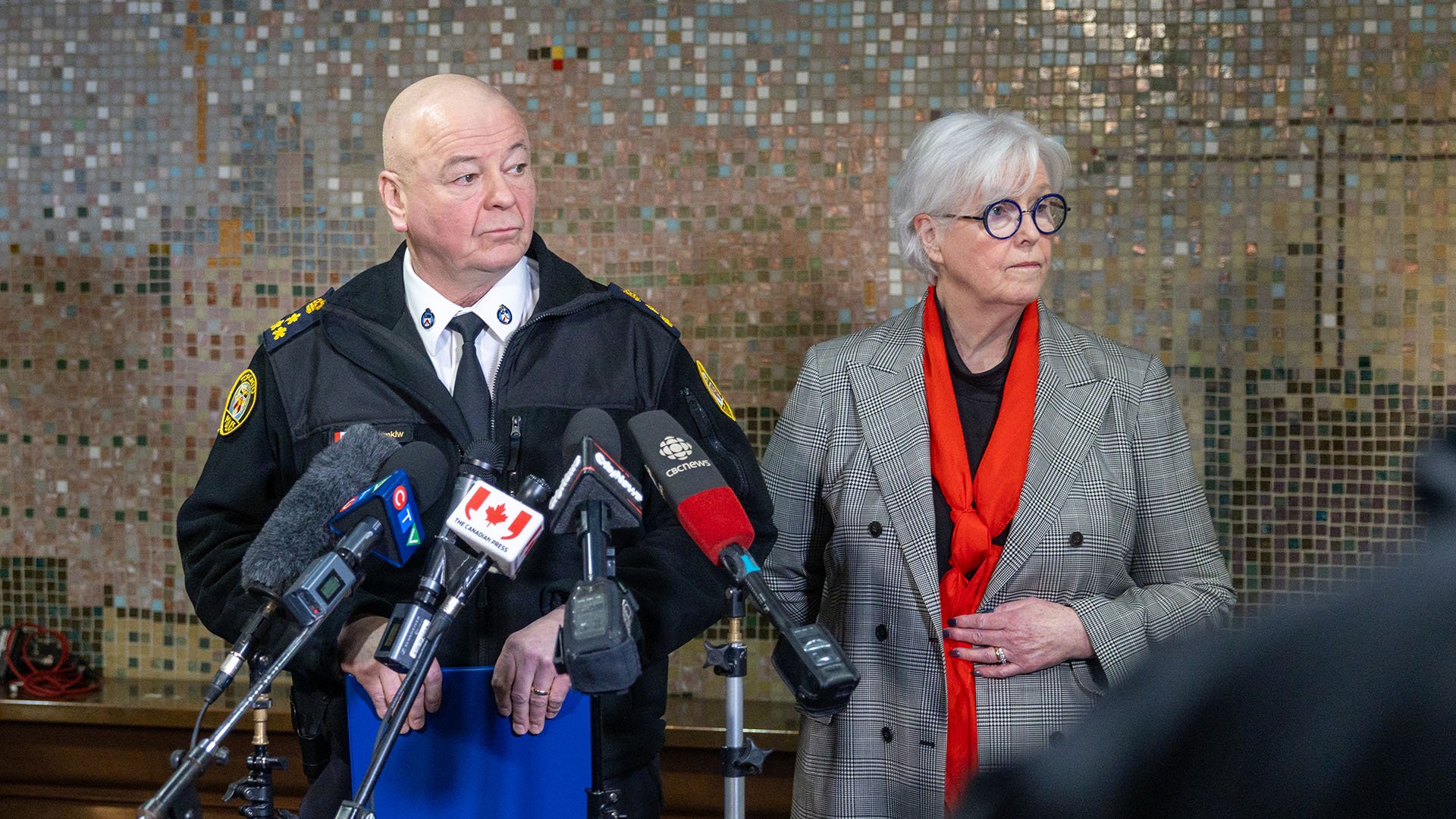 Two people stand in front of microphones