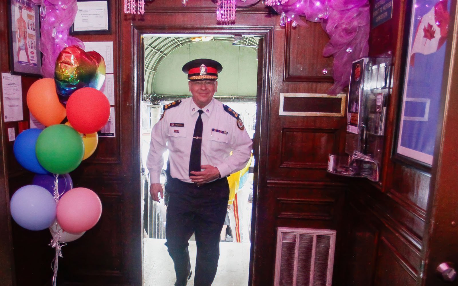 man in a police uniform at the doorway of a pub with baloons and other decorations around it