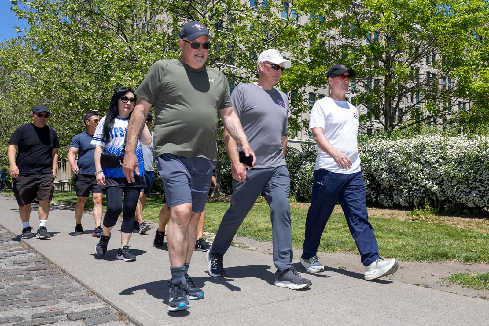 group of men and women walking along a paved path surrounded by the trees