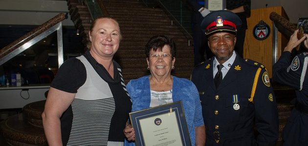 Three people stand together, one holds framed certificate