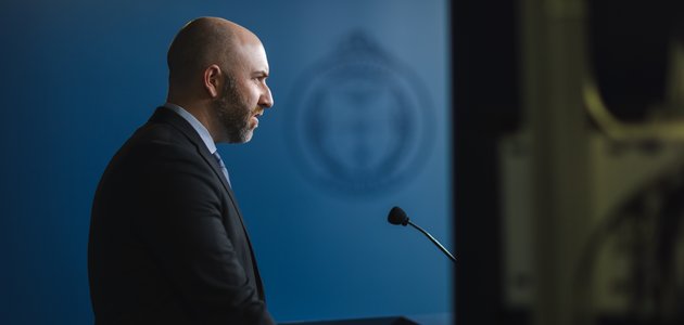 A man in a suit speaks into a microphone