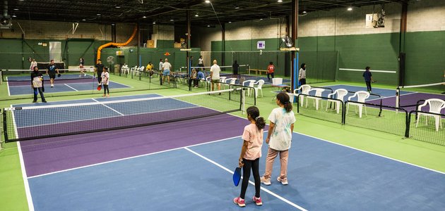 large indoor area with multiple fields each having a net across the field