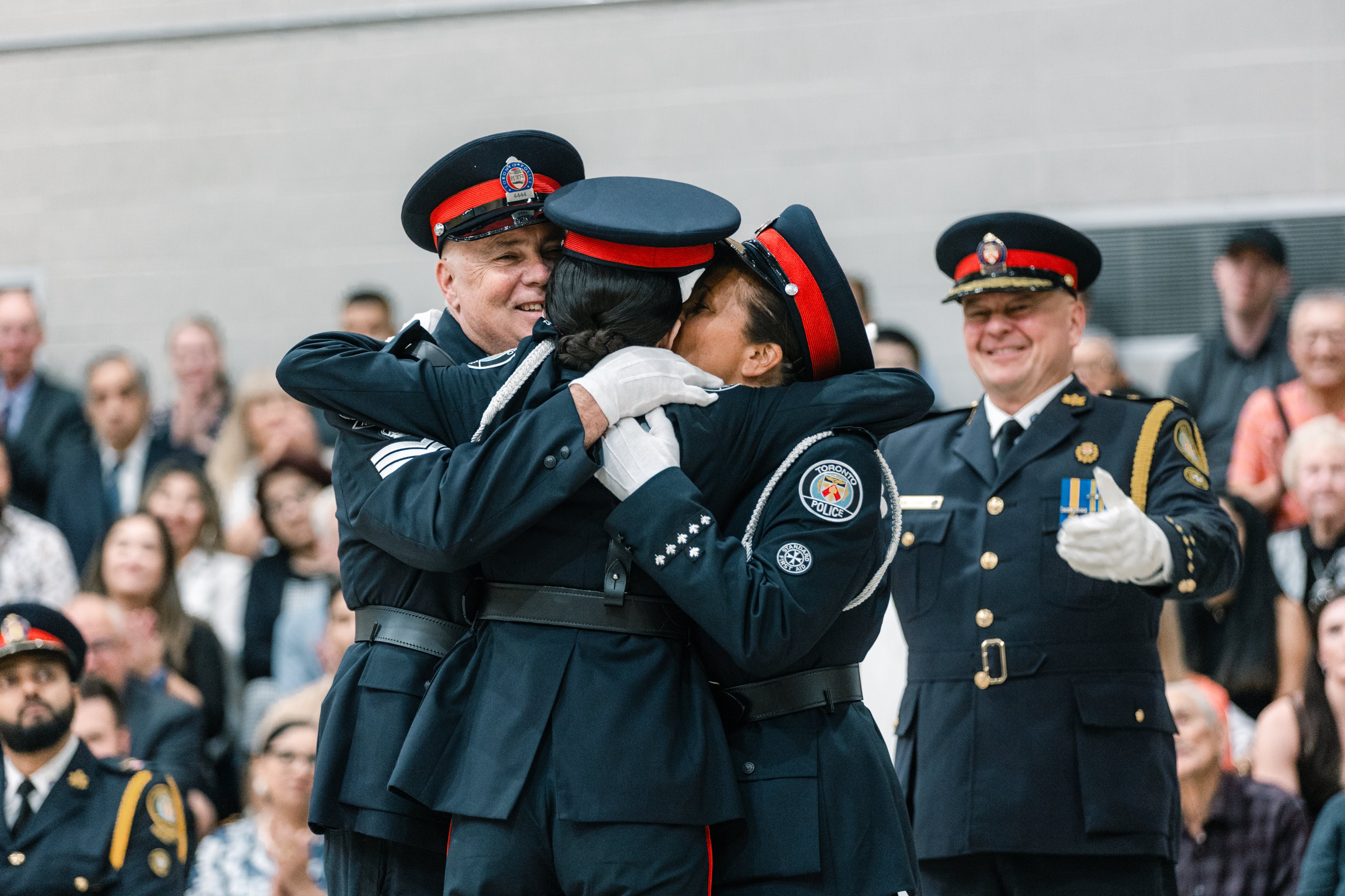 Three police officers share a hug while the Chief looks on