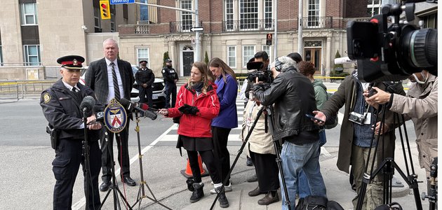 Reporters record a police officer in front of microphones
