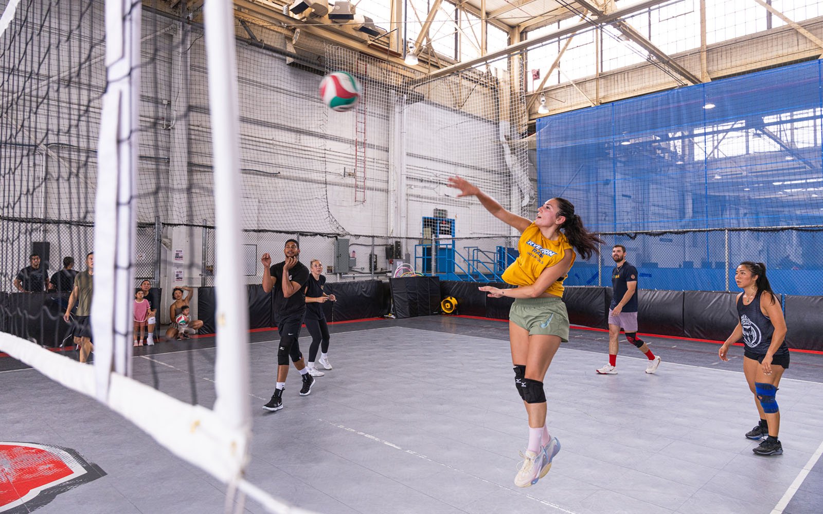 group of men and women playing volleyball in an indoor court