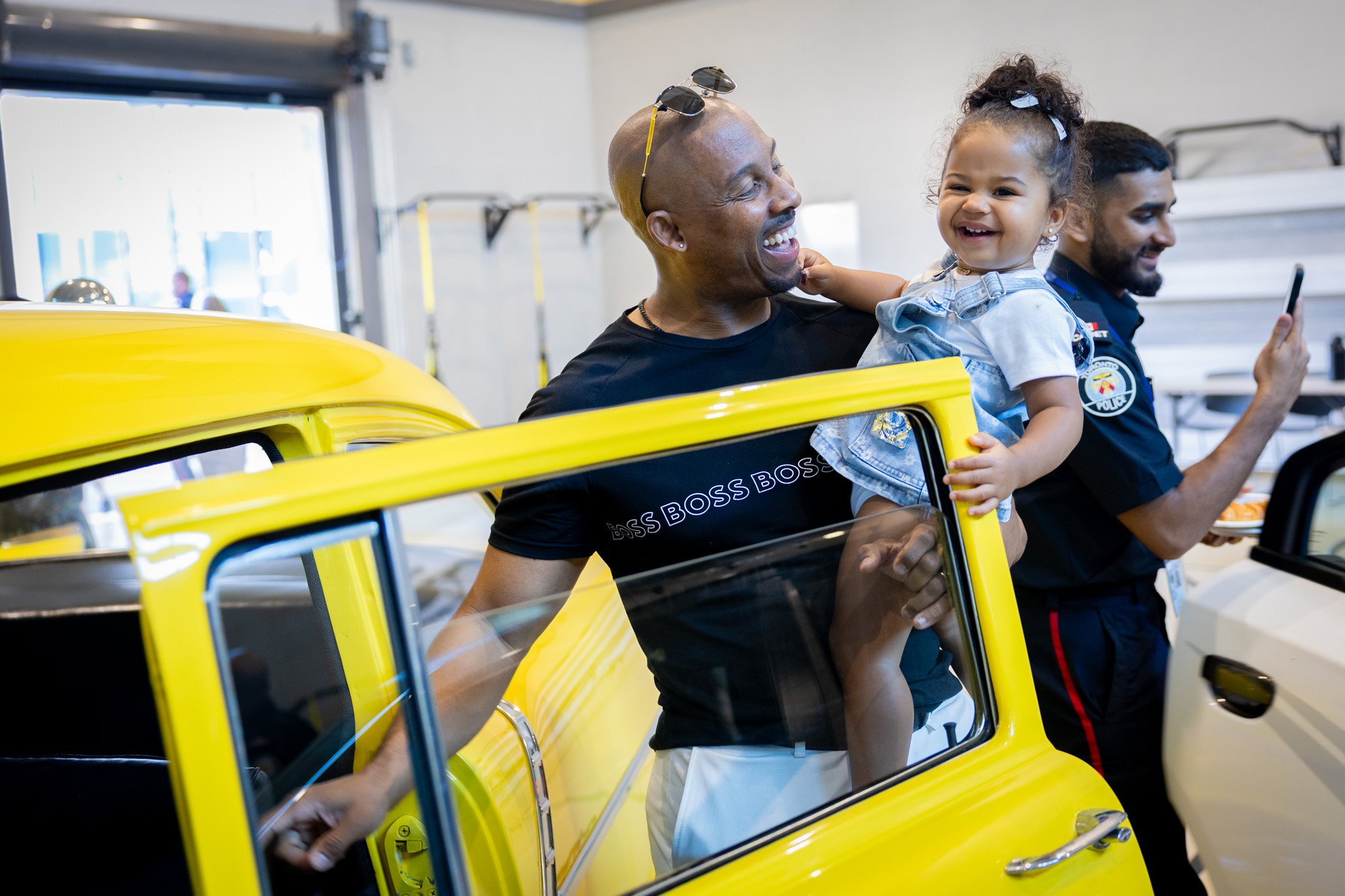 A man holding a child next to a yellow car