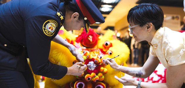Two people use paint brushes on a costume figure