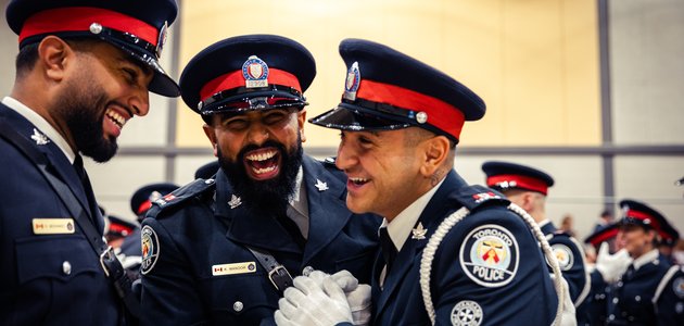 Three police officers in a smiling embrace
