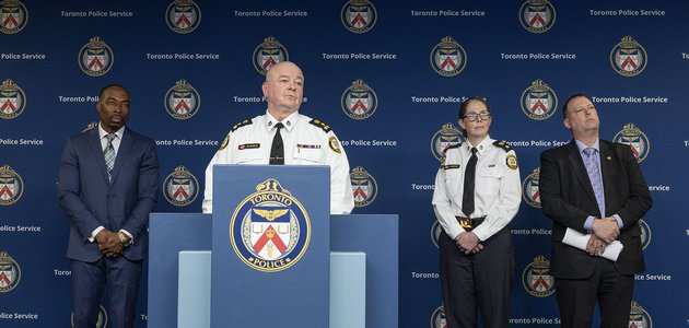 Police officer at a podium alongside three other people