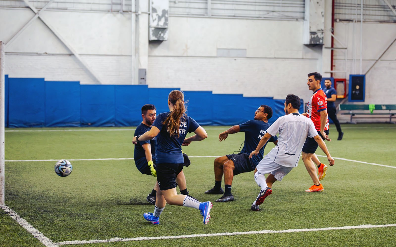 group of men and women playing soccer in an indoor field