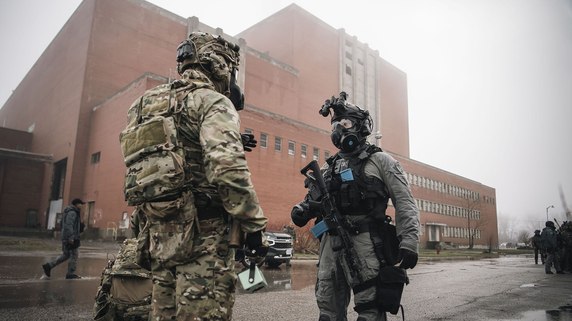 Two men in uniform and gas masks speaking