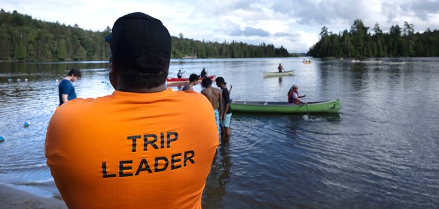 Person standing while people canoe and swim