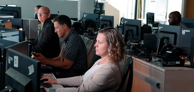 group of people in a large room sitting in front of computer screens