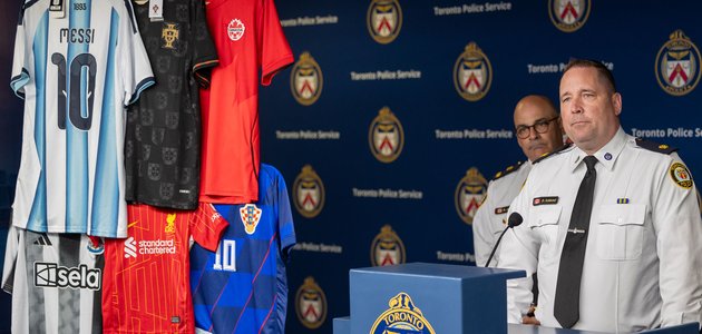 photo of two men in uniforms at a podium with soccer jerseys hanging to their side