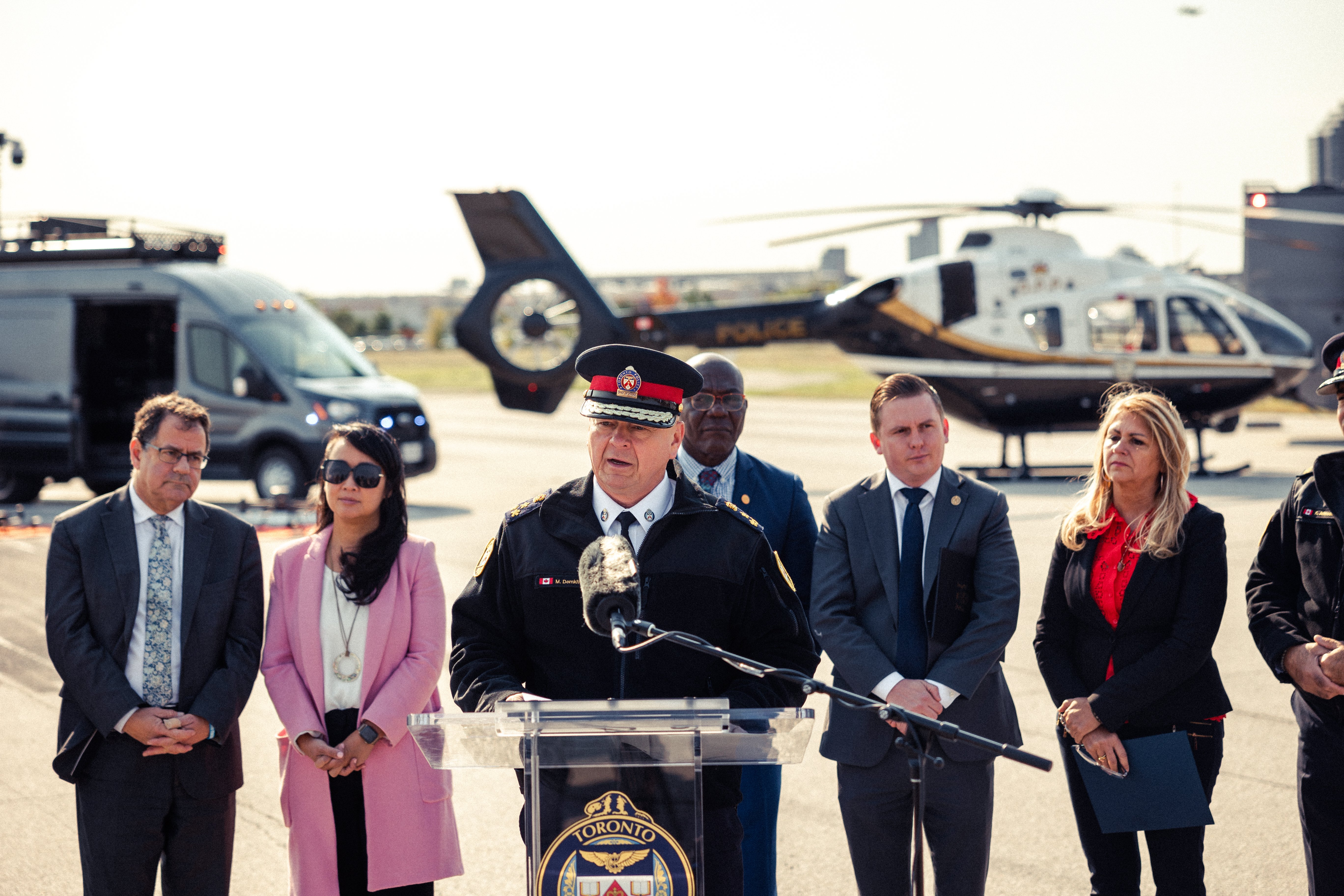 A police officer speaks with a helicopter in the background