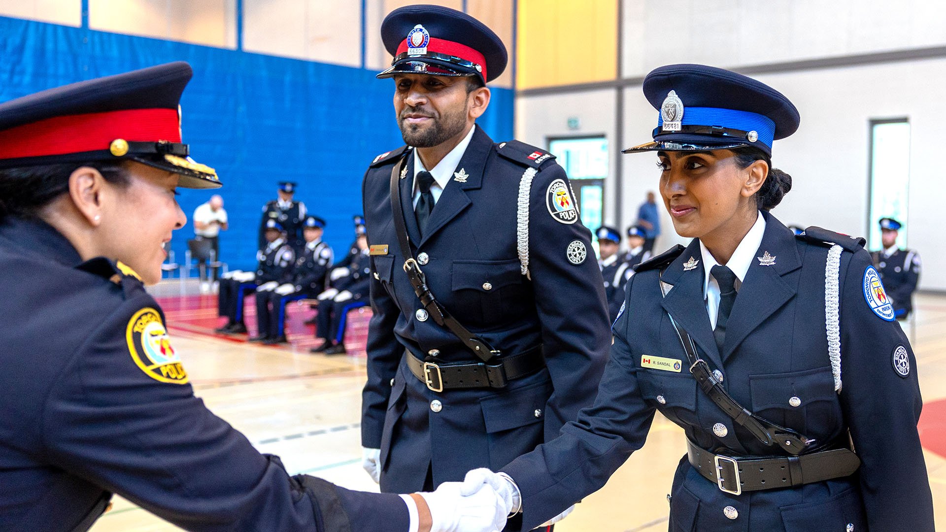 Three people in uniform, two shake hands