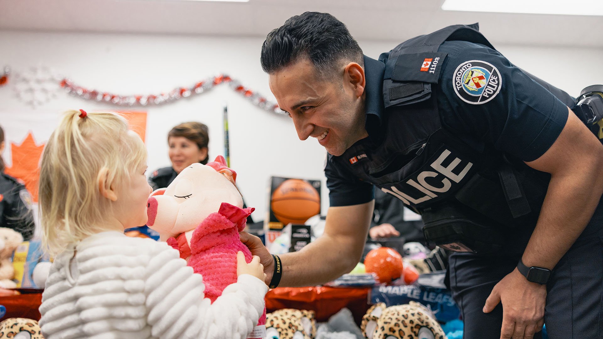 Police officer handing stuffed animal to child