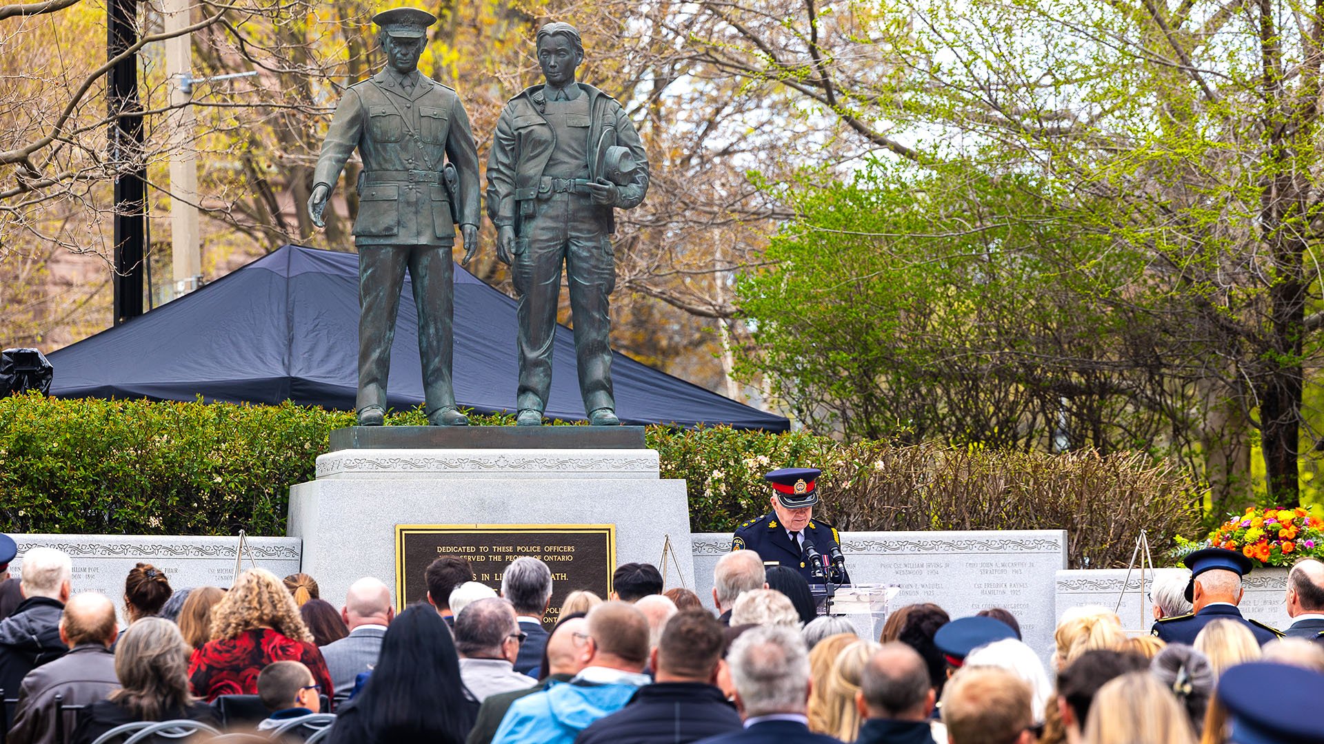 People seated in front of a memorial wall