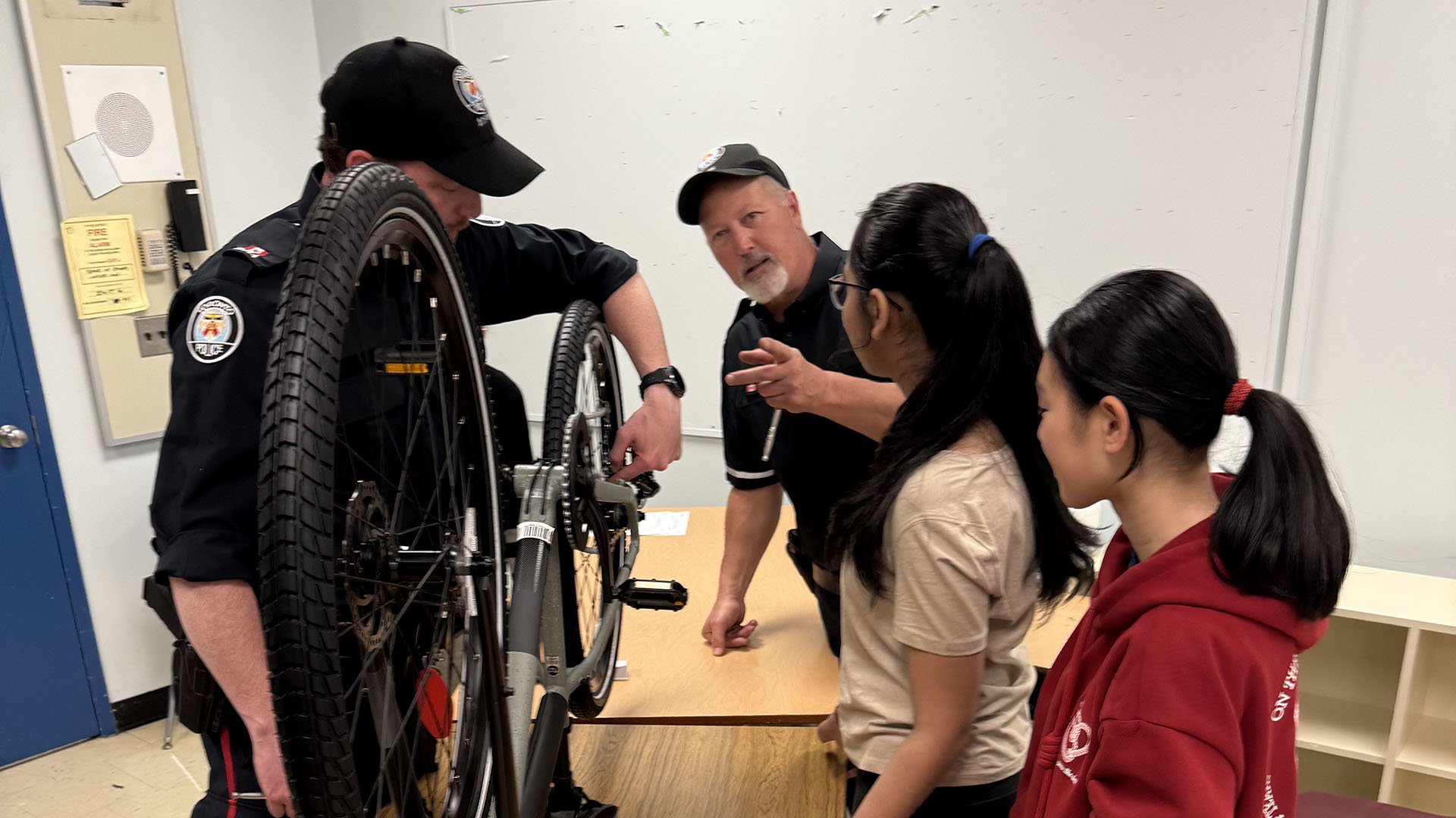 Two police officers with two young people fixing a bike
