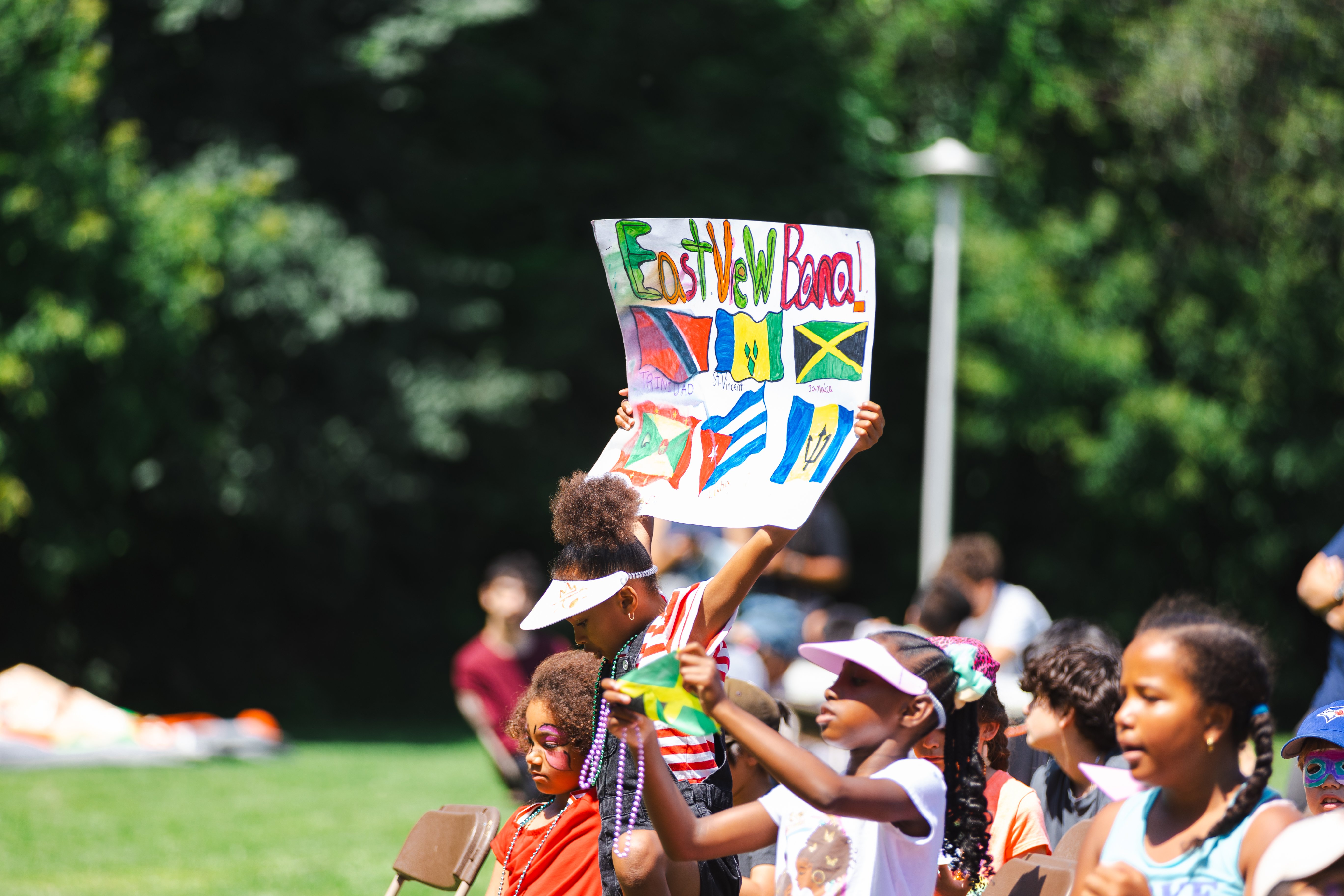 A sign being held up showcasing different Caribbean flags