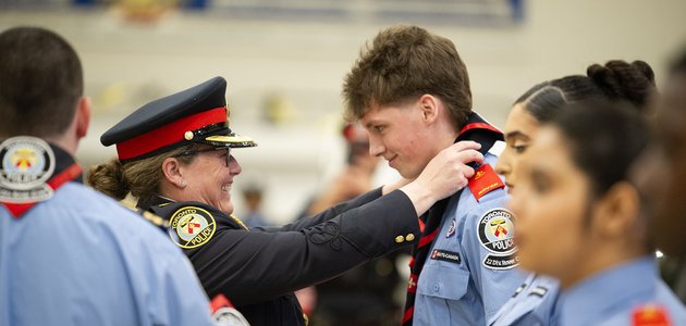 Police officer puts a necker chief on a Rover Crew member