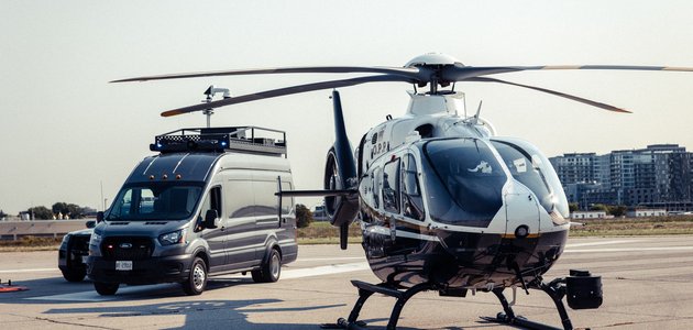A helicopter and a police command vehicle on a runway