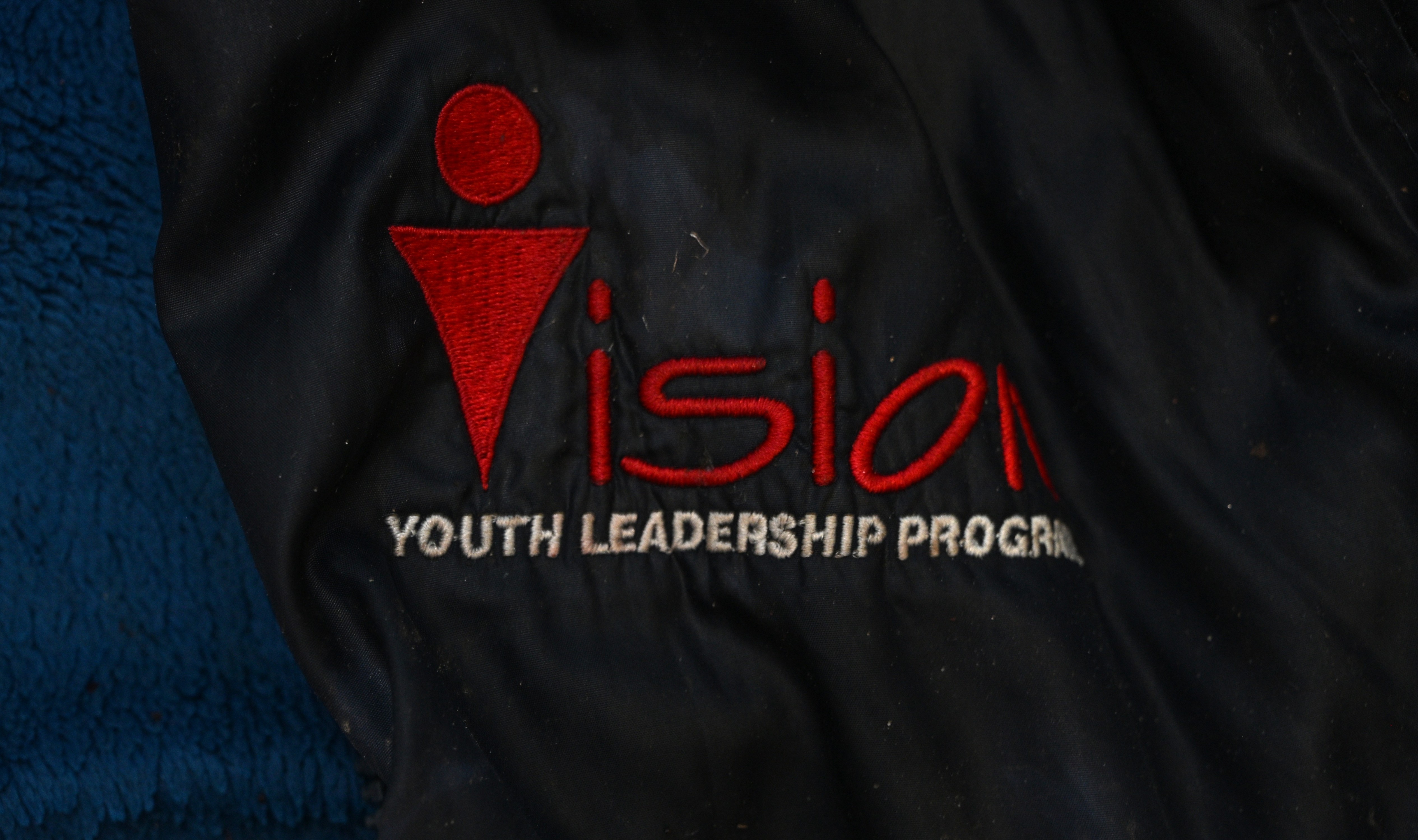 Black jacket worn by victim with "vision youth leaders program" written on it.