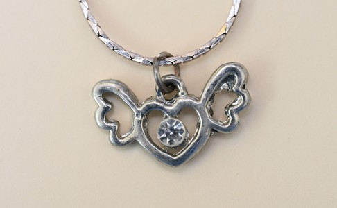 Necklace worn by victim with a silver heart-shaped pendant with wings and a single clear stone in the centre
